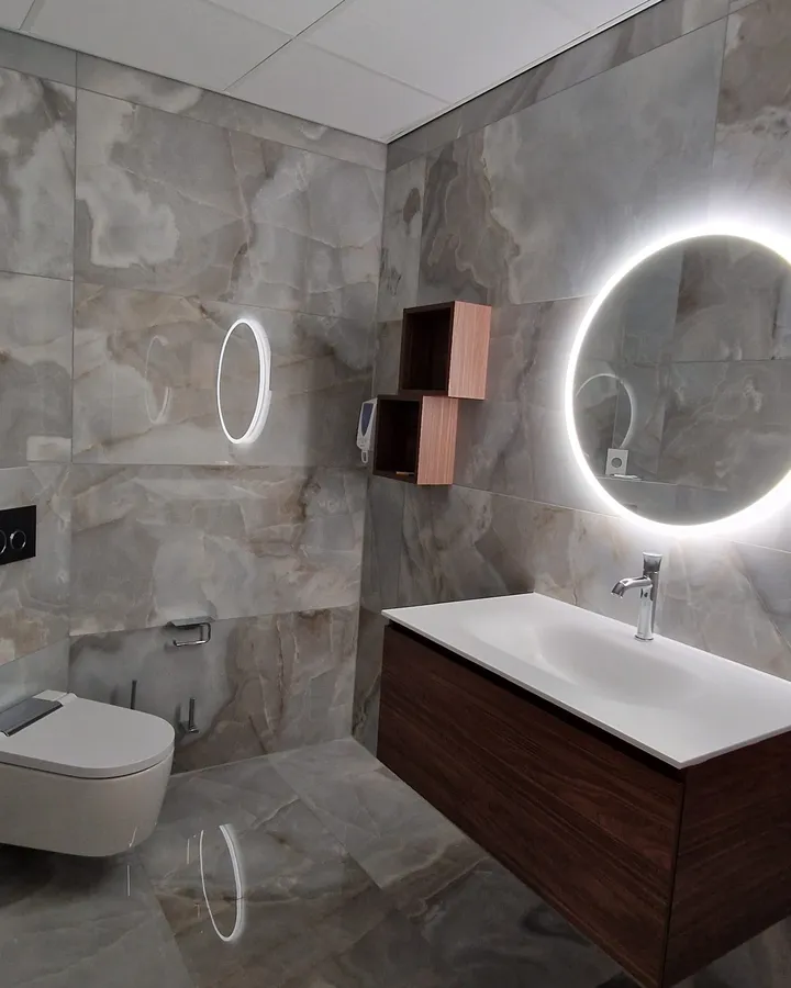 Salle de bains avec carrelage effet pierre, vasque et miroir rond lumineux